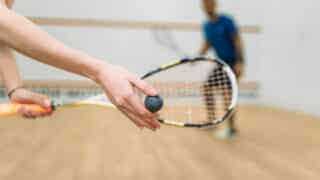 Young couple with rackets play squash game in indoor training club. Active sport lifestyle. Recreation workout, match with racquet