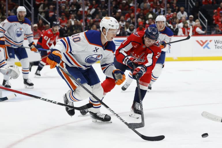 Nov 19, 2025; Washington, District of Columbia, USA; Edmonton Oilers center Trent Frederic (10) and Washington Capitals center Aliaksei Protas (21) battle for the puck during the third period at Capital One Arena. Mandatory Credit: Geoff Burke-Imagn Images